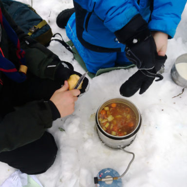 Kuvassa talvikisan osallistujat kokkaavat ruokarastilla