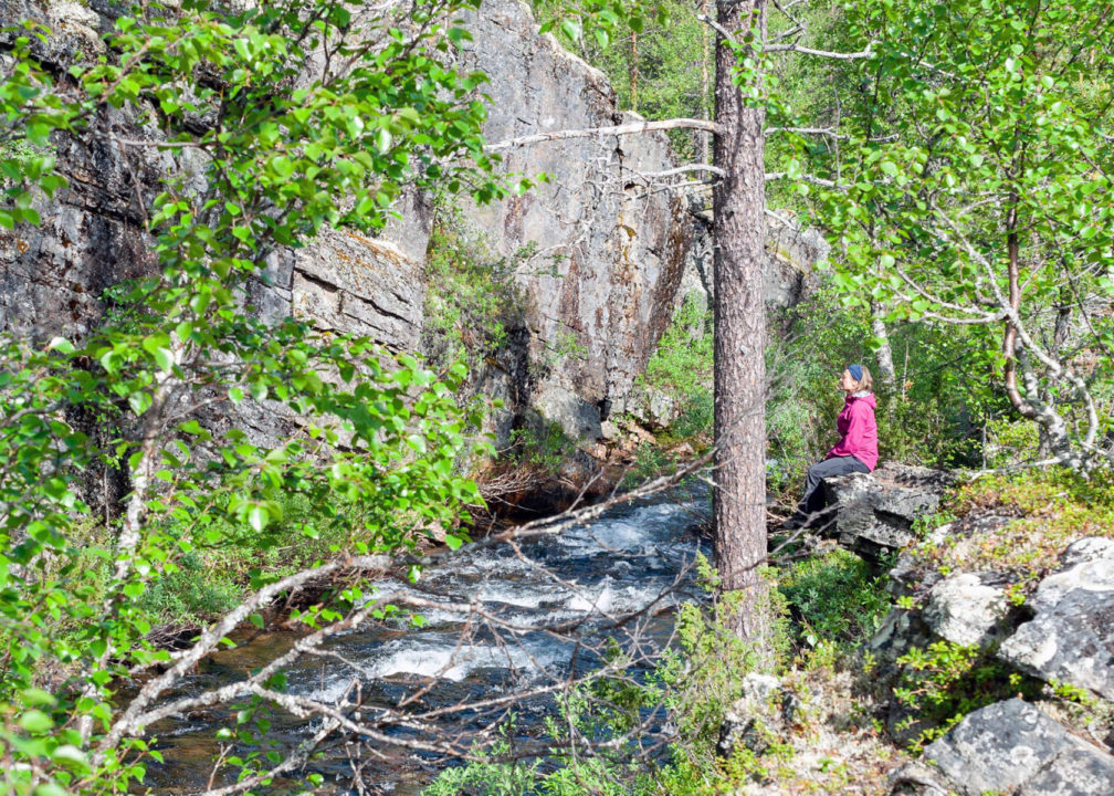 Kuvassa partiolainen levähtää puron äärellä.
